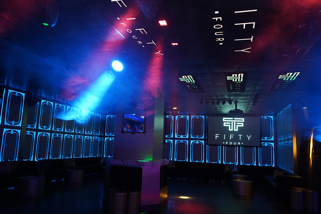 The image shows an interior space that appears to be a nightclub or entertainment venue, with a dimly lit ambiance and colorful lighting effects.